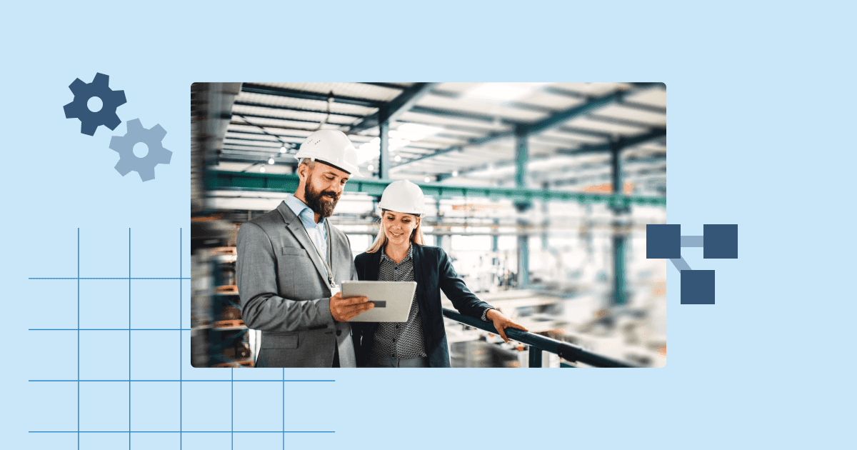 Two site managers wearing hard hats and business attire reviewing data on a tablet inside an industrial facility.