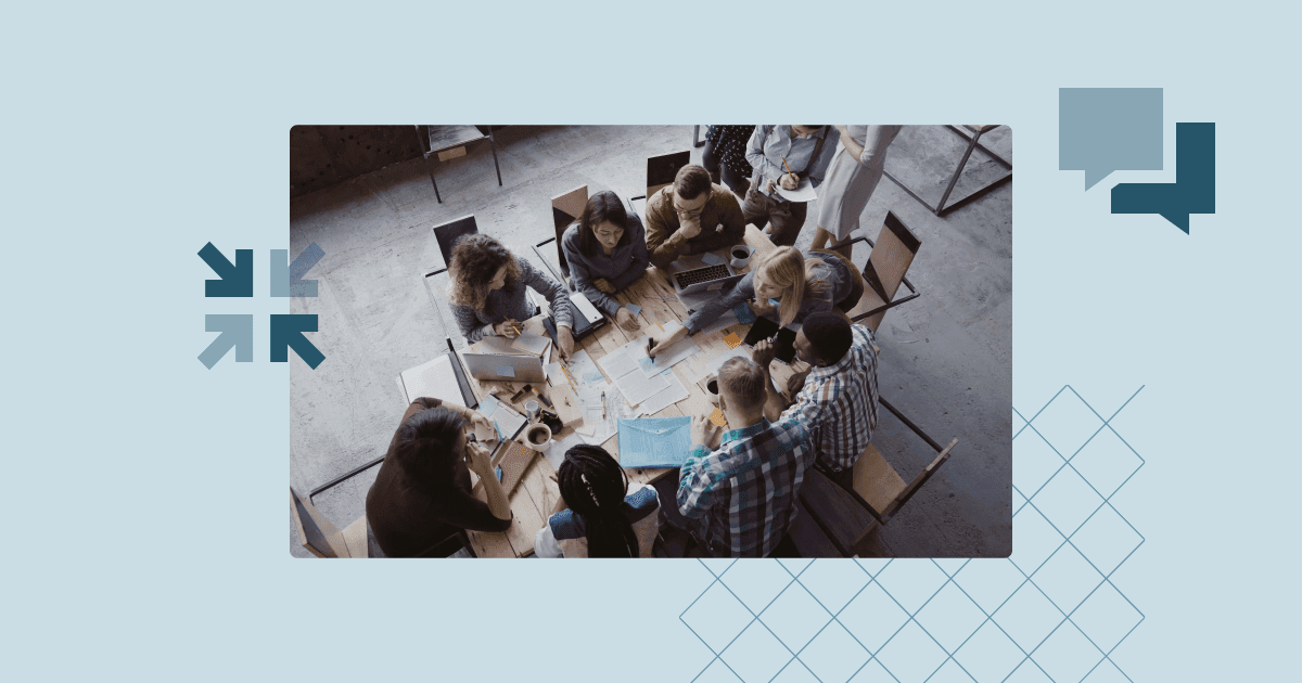 Top-down view of a committee team working together around a meeting table with documents and laptops.