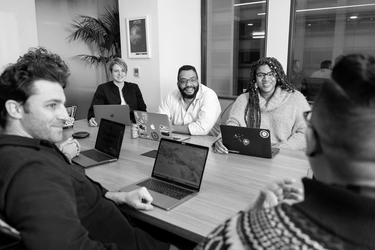 five people attending a meeting with their laptop